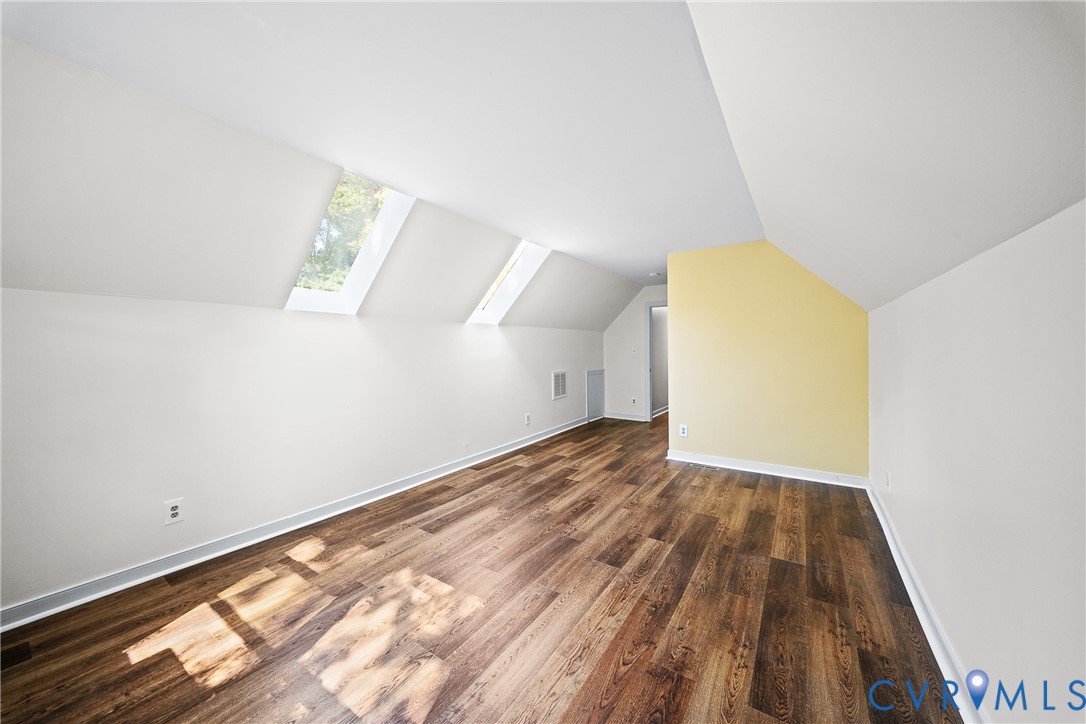 Vaulted ceiling featuring two skylights and wood-finish flooring