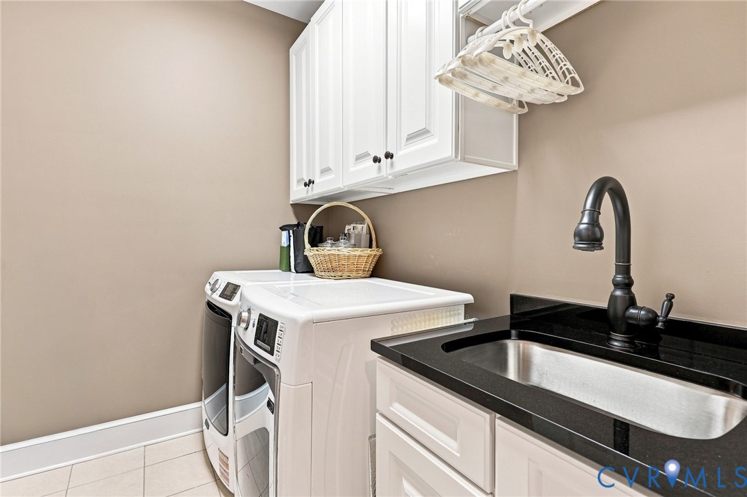 Laundry area featuring white cabinetry, a dark countertop, an undermount sink, and a dark-finish faucet