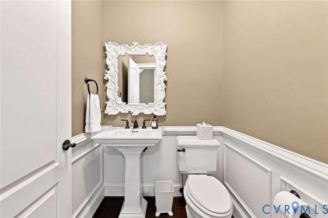 Pedestal sink with dark-toned fixtures, ornate framed mirror, and wainscoting