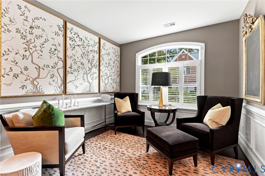 Arched window with plantation shutters, dark wood-finish flooring, wainscoting, and decorative wall panels