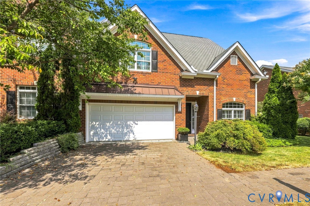 Brick exterior with a gabled roofline, two-car garage, and a paver driveway