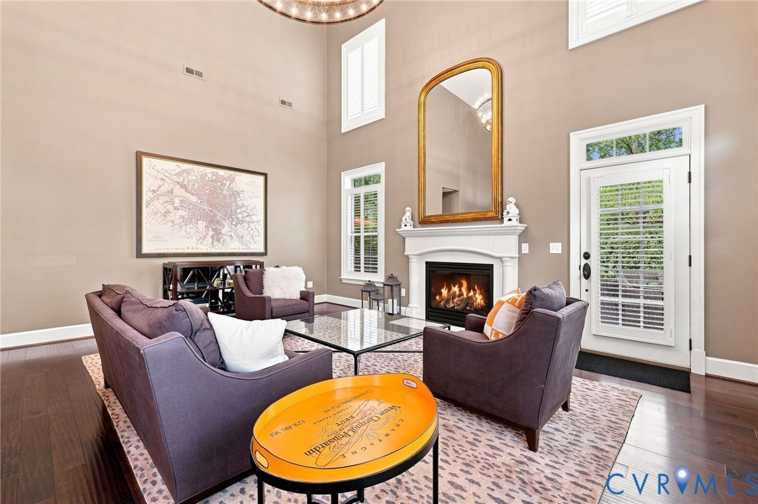 Vaulted ceiling, dark wood-finish flooring, white fireplace mantel, gas fireplace insert, and white door with integrated blinds