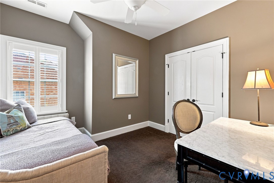 3rd guest room featuring neutral wall paint, wide trim, a ceiling fan/light, and double door closet with custom organization