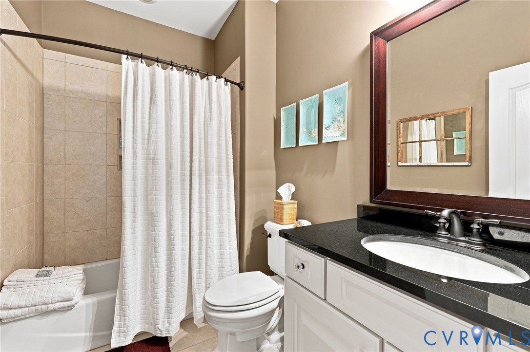 Bathroom featuring a tub/shower with tiled surround, granite top sink, and framed mirror