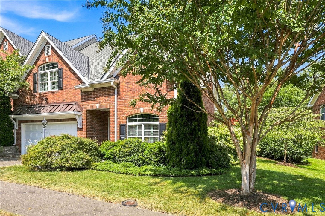 Brick-front residence with an attached two-car garage, arched windows, and a covered entry