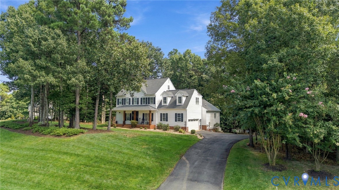 White two-story residence with dormer windows, a covered front porch, and a paved driveway