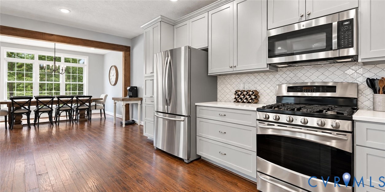 Kitchen featuring stainless steel appliances, light gray cabinetry, white countertops, and a decorative tile backsplash