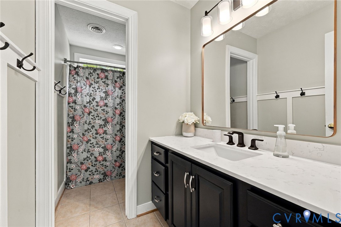 Vanity featuring a white countertop with an integrated sink, dark cabinetry, and black fixtures