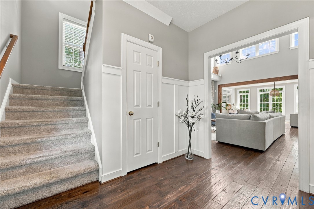 Hardwood flooring, wainscoting, and a carpeted staircase