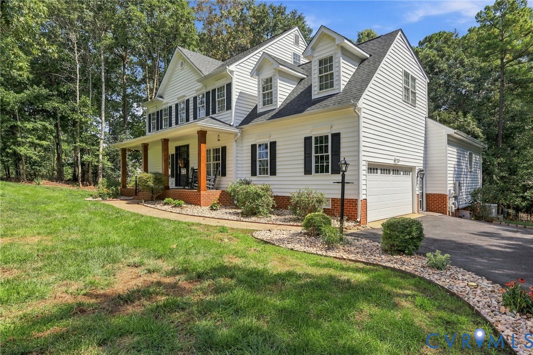 Classic white siding exterior with a covered front porch featuring wood columns, a two-car garage, and dormer windows Classic white siding exterior with a covered front porch featuring wood columns, a two-car garage, and dormer windows