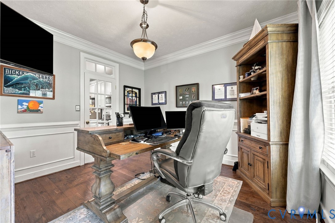 Hardwood flooring, crown molding, wainscoting, glass-paneled door, and a built-in wood cabinet