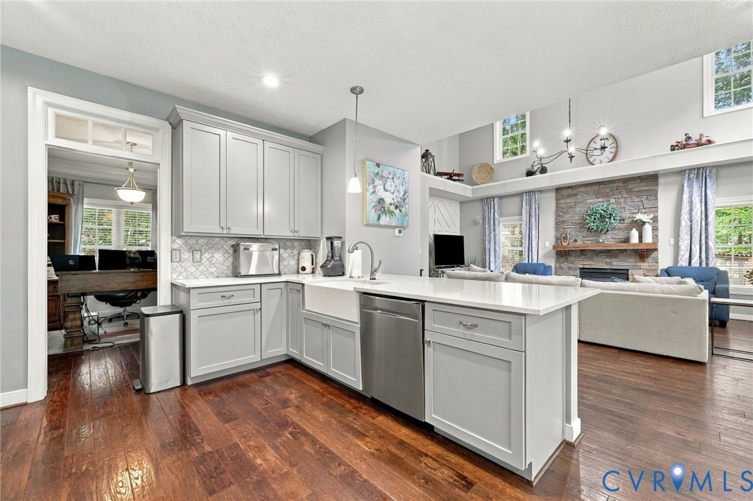 Hardwood flooring throughout, kitchen featuring light gray cabinetry, white countertops, an apron-front sink, and stainless steel appliances