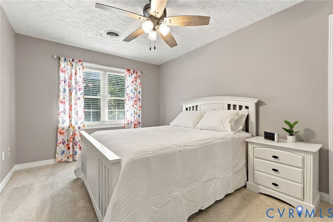 Carpeted room featuring neutral wall tones, a ceiling fan with integrated lighting, and a double-pane window