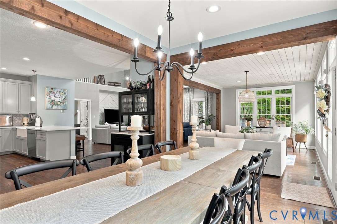 Exposed wood beams, wood-finish flooring, white shiplap ceiling, recessed lighting, and large windows