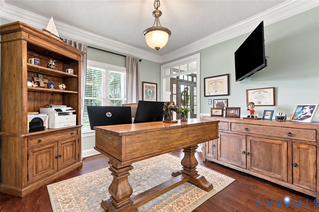 Wood-finish flooring, crown molding, a built-in shelving unit, and a built-in storage cabinet