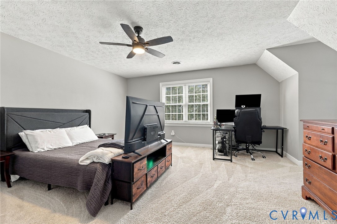 Carpeted room featuring a ceiling fan with light,%