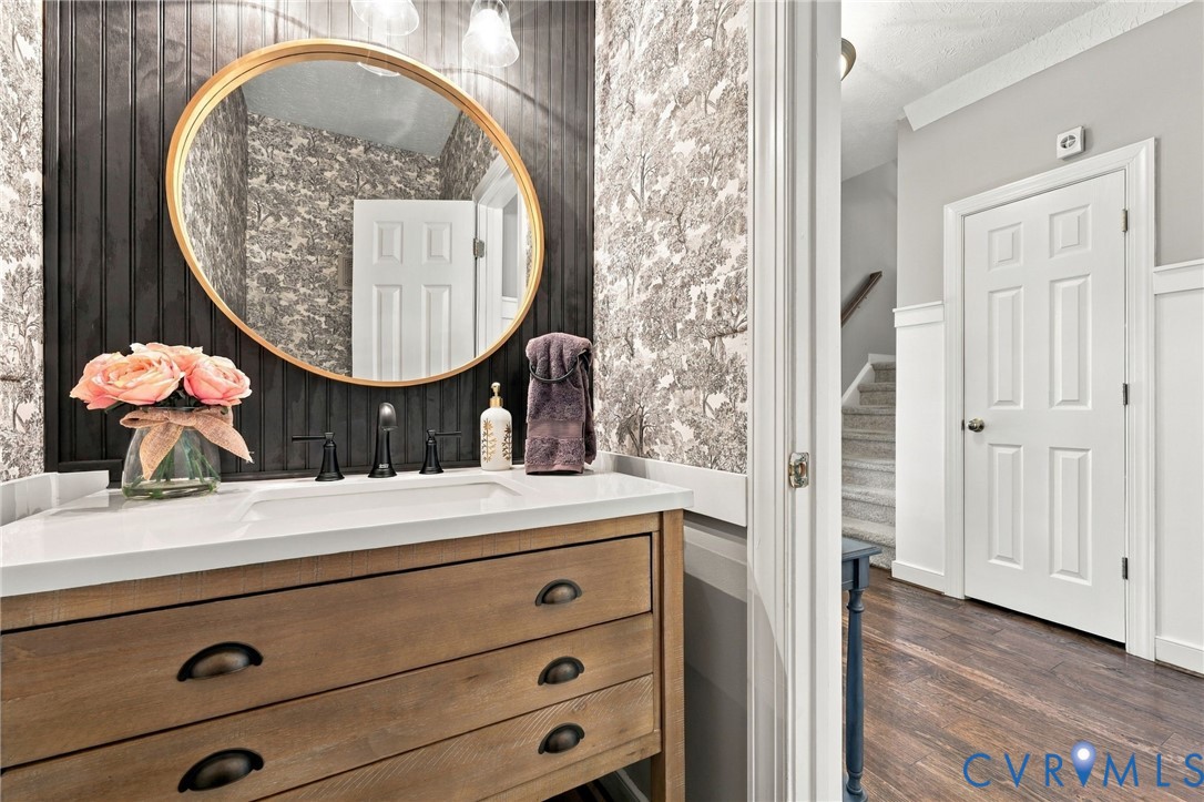 Vanity with a wood-finish base, integrated white sink, and dark bronze hardware