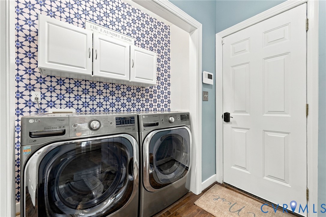 White cabinetry, patterned wall covering, wood-finish flooring, and white paneled door