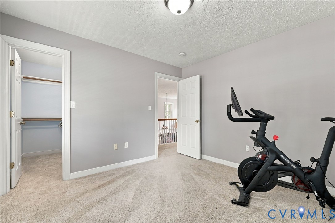 Neutral-toned walls, plush carpeting, and a built-in closet with shelving and hanging rods