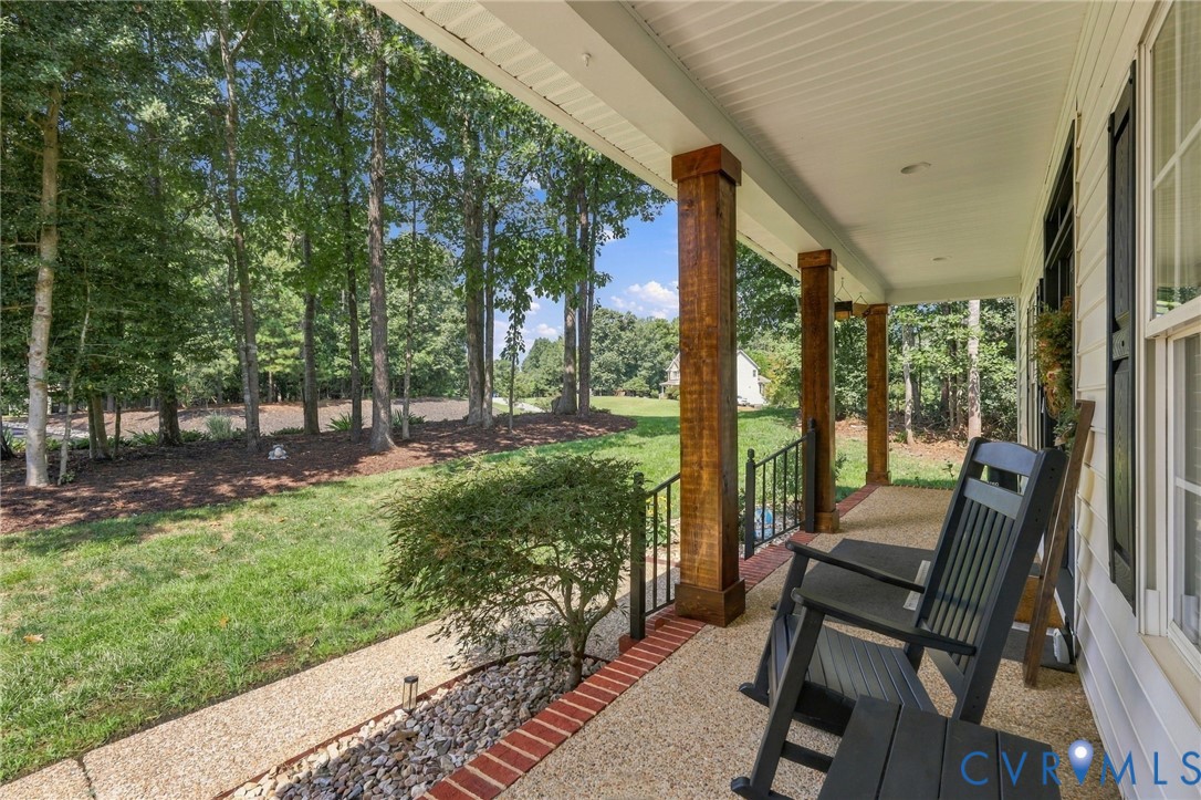 Expansive covered front porch with wood-finish columns, exposed aggregate flooring
