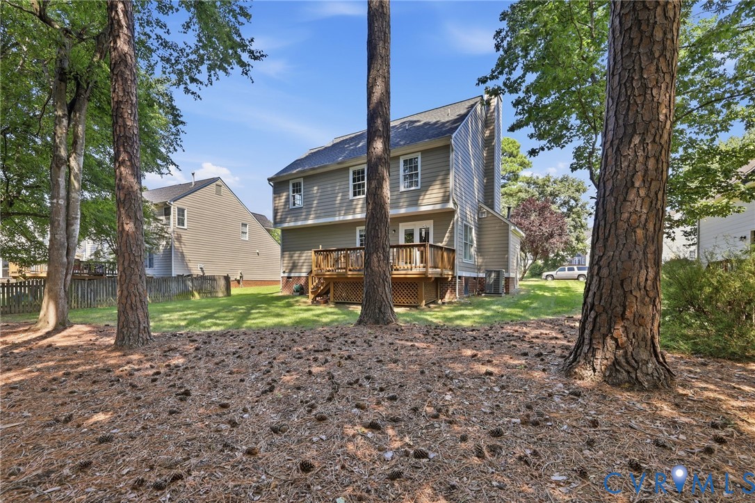 Expansive rear yard featuring mature trees, a wood deck, and a grass lawn