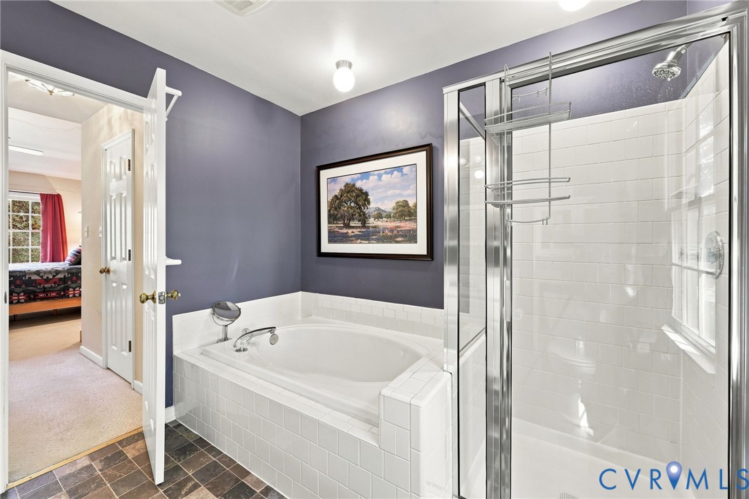 Built-in soaking tub with white tile surround, glass-enclosed shower with subway tile walls, and slate-finish flooring