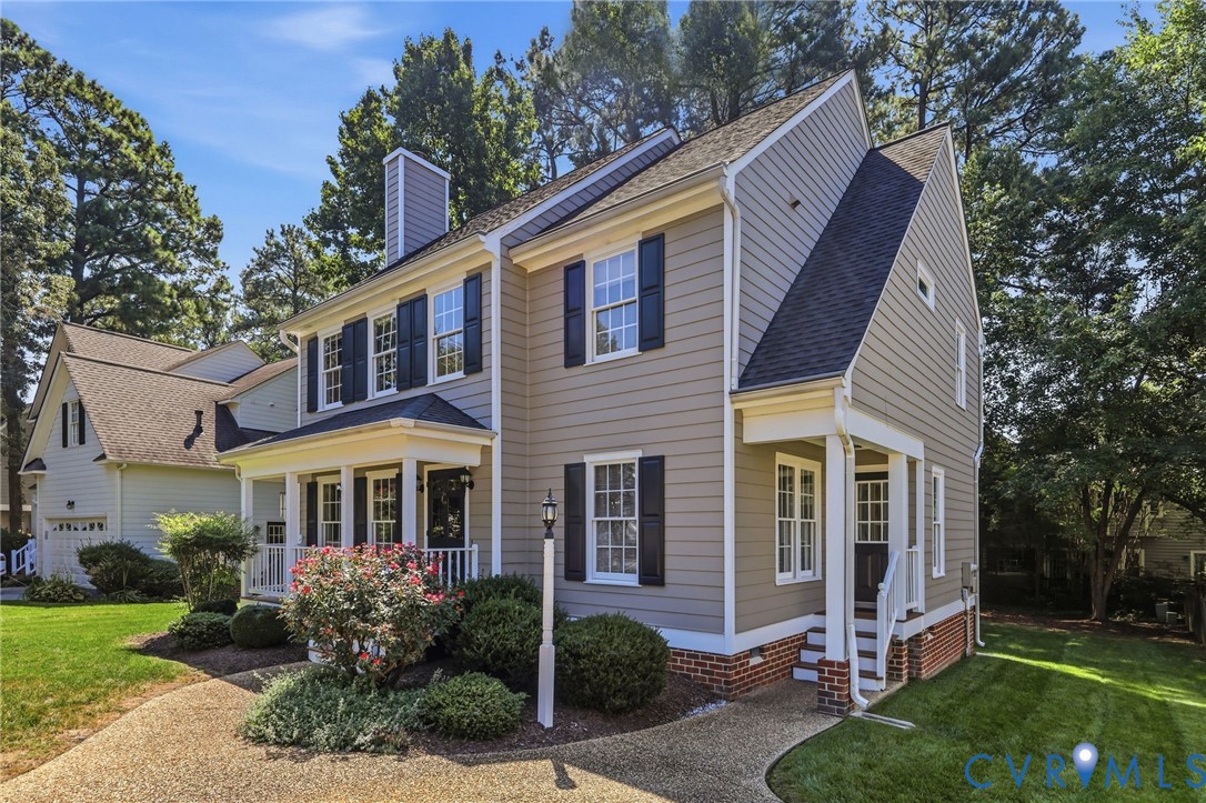 Multi-level siding exterior with a covered entry, dark shutters, and a brick foundation