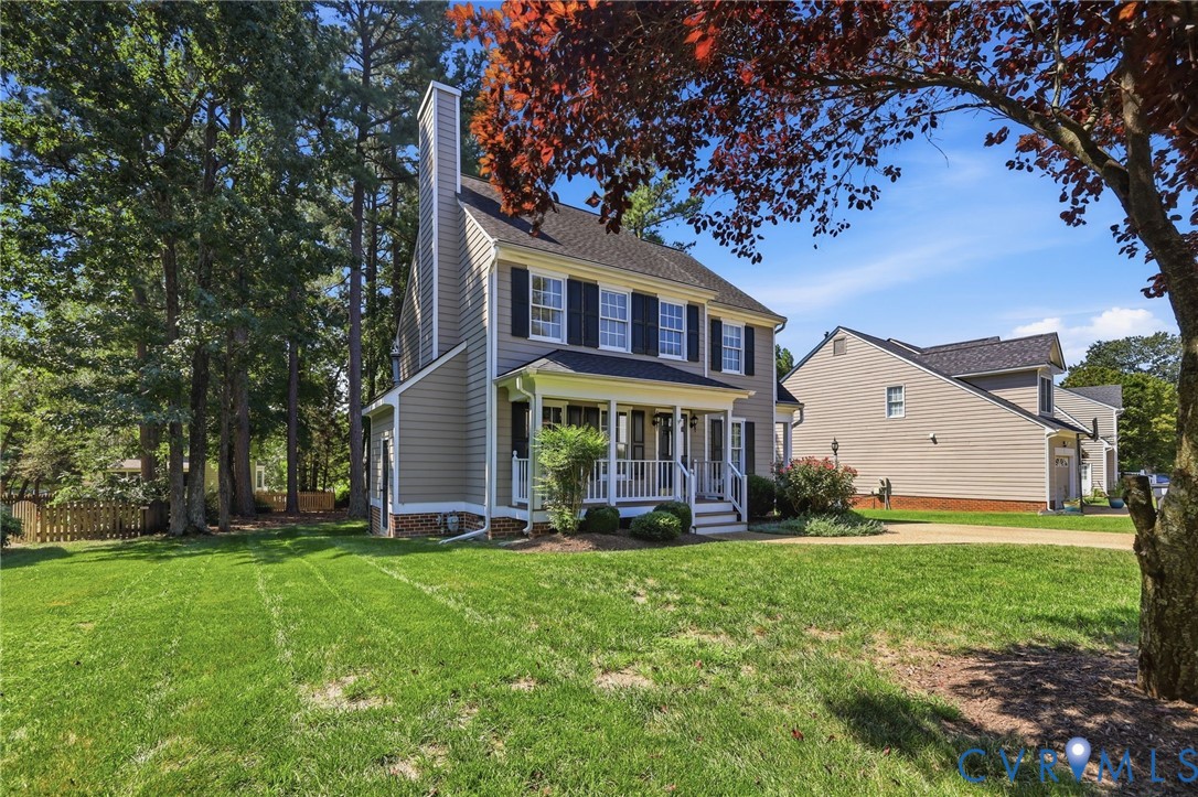 Two-story residence featuring a covered front porch, exterior chimney, and dark-paneled shutters