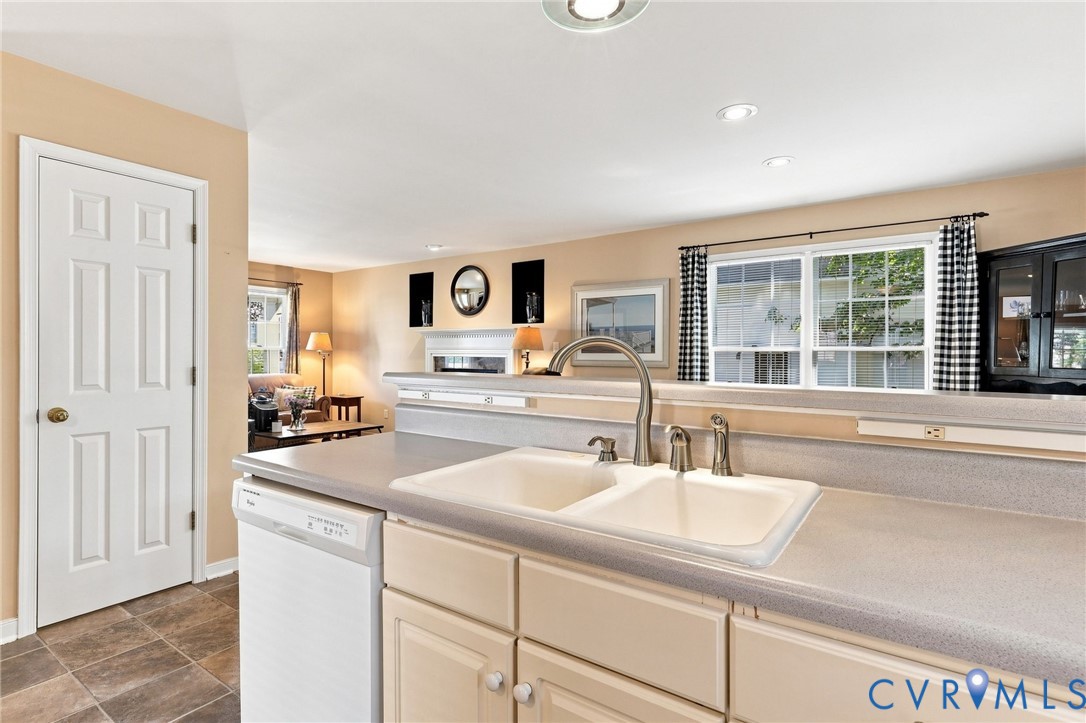 Kitchen featuring a double basin sink with a gooseneck faucet, light-toned cabinetry, and integrated dishwasher