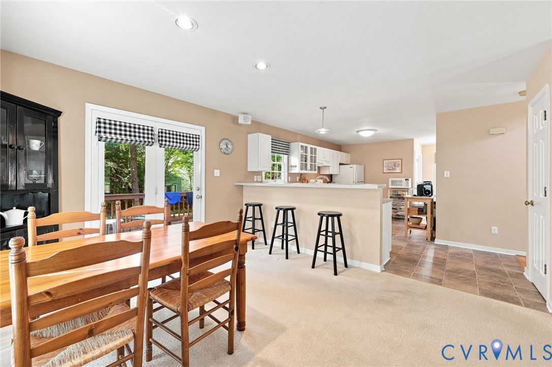 Open-concept living and dining area with wood-finish flooring, recessed ceiling lighting, and French doors opening to outdoor space