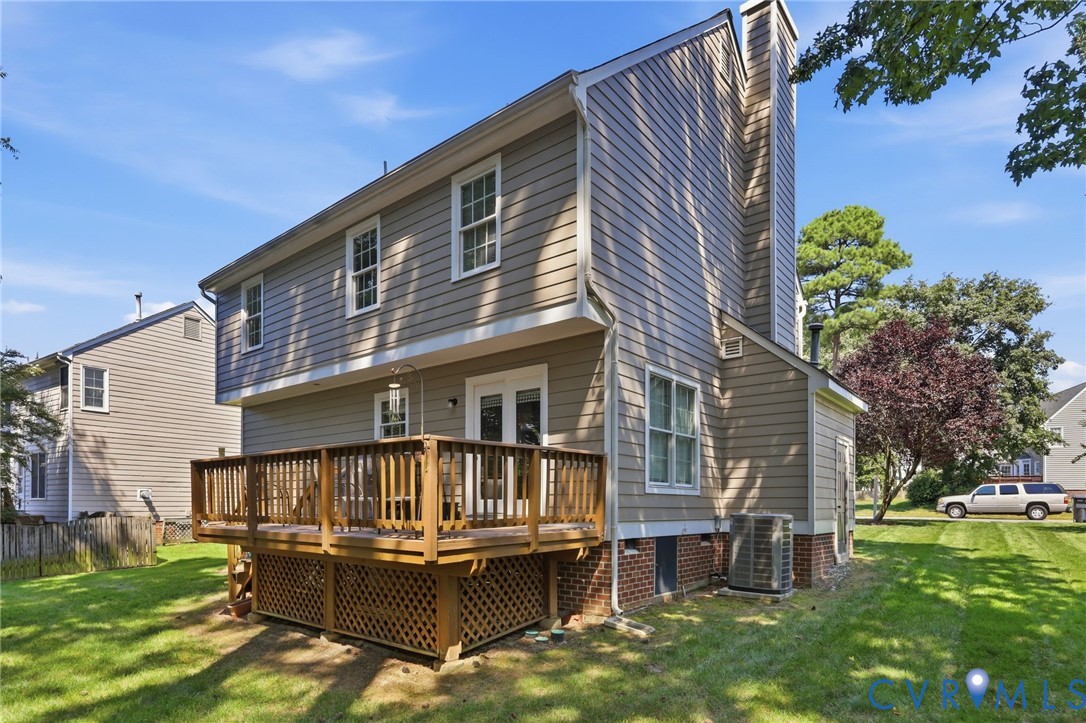 Exterior featuring light brown siding, a multi-level wood deck, white-framed windows, and a prominent chimney structure