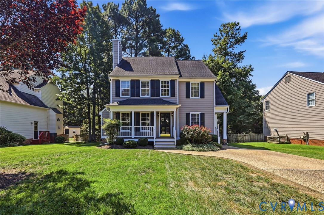 Two-story residence with a covered front porch, a gray siding exterior, dark shutters, and a prominent chimney