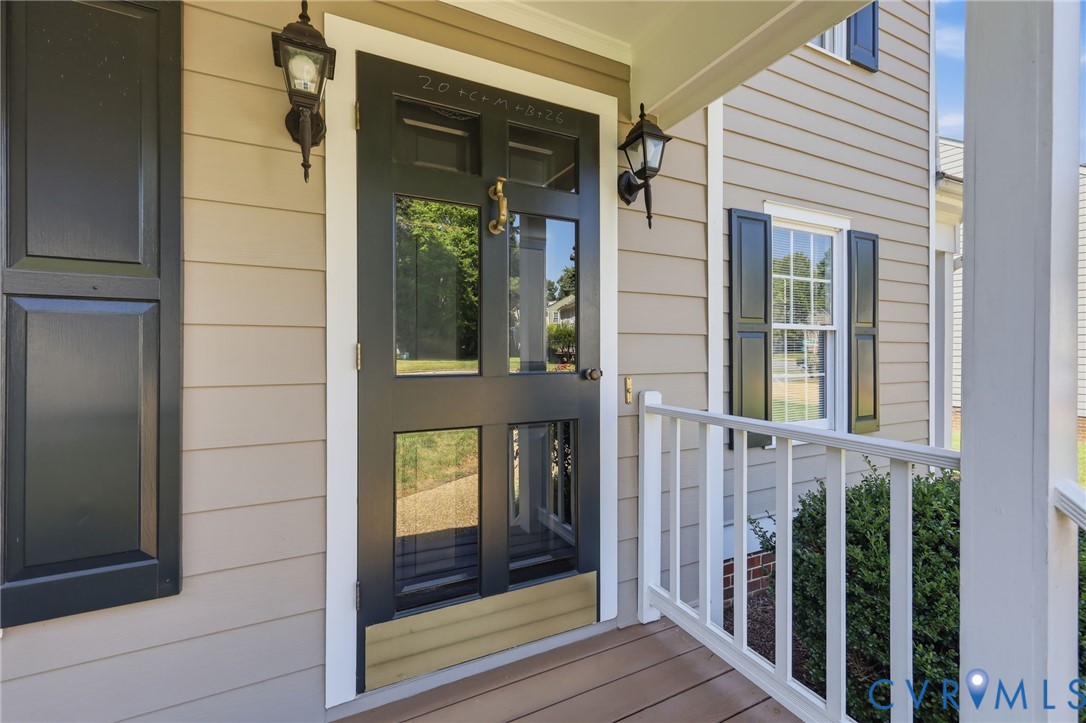 Front entry featuring a paneled door with glass inserts, exterior light fixtures, a white railing, and horizontal siding