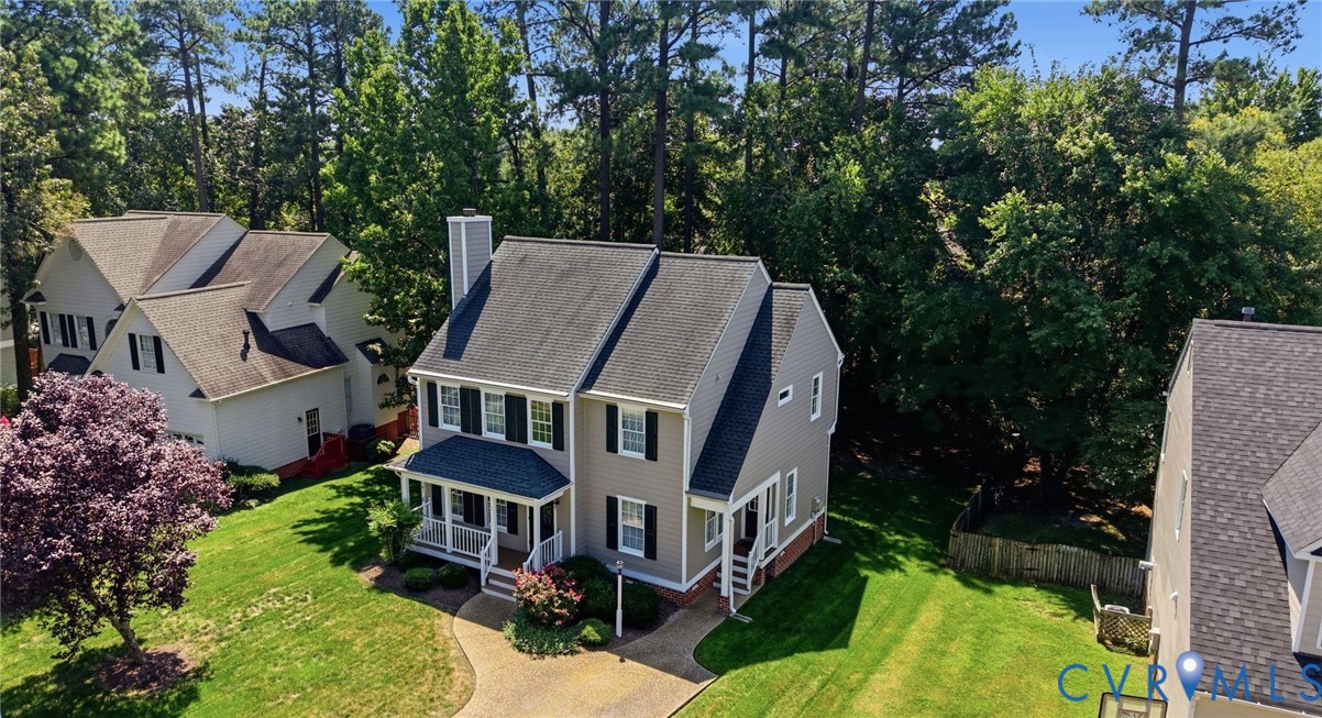 Two-story exterior with a covered porch, an attached chimney, and a paved driveway