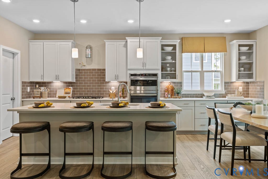 Kitchen featuring a center island, light-toned cabinetry, subway tile backsplash, and stainless steel appliances