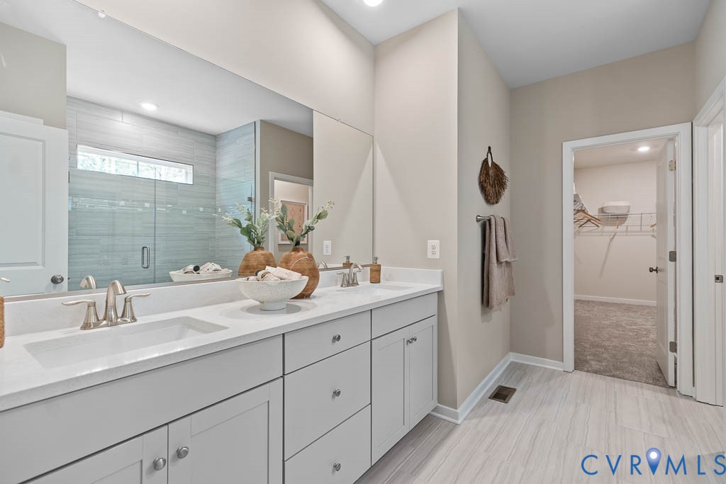 Dual vanity with integrated sinks, brushed nickel fixtures, light gray cabinetry, and a full-width mirror