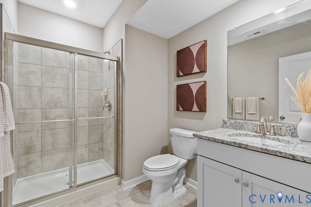 Enclosed shower with sliding glass doors, a vanity with white cabinetry, a light-toned granite-finish countertop, and a built-in sink