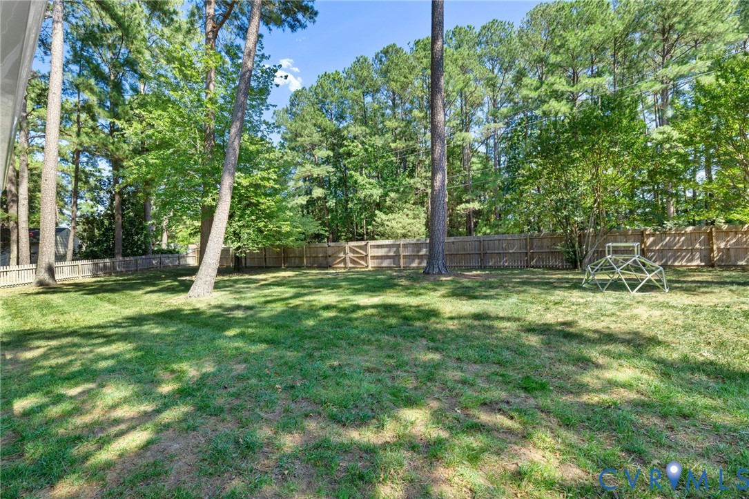 Expansive lawn area, mature trees, wood fence enclosure, and additional picket fencing