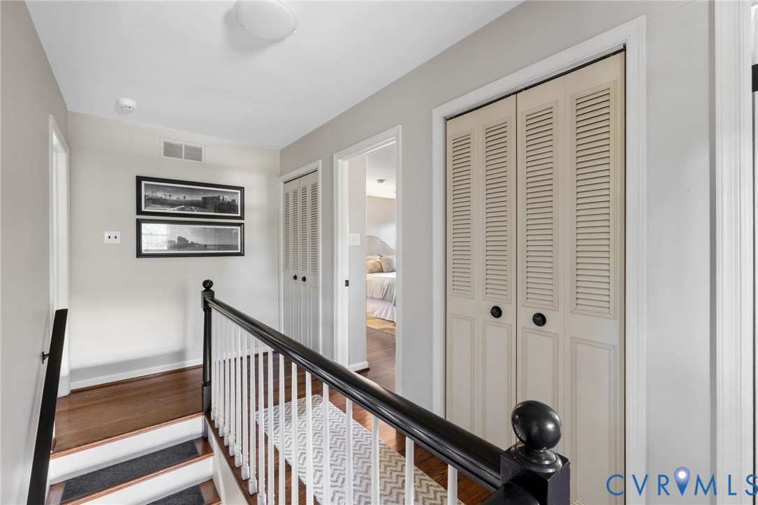 Upstairs landing. Hardwood flooring, white trim, and two bi-fold louvered closets