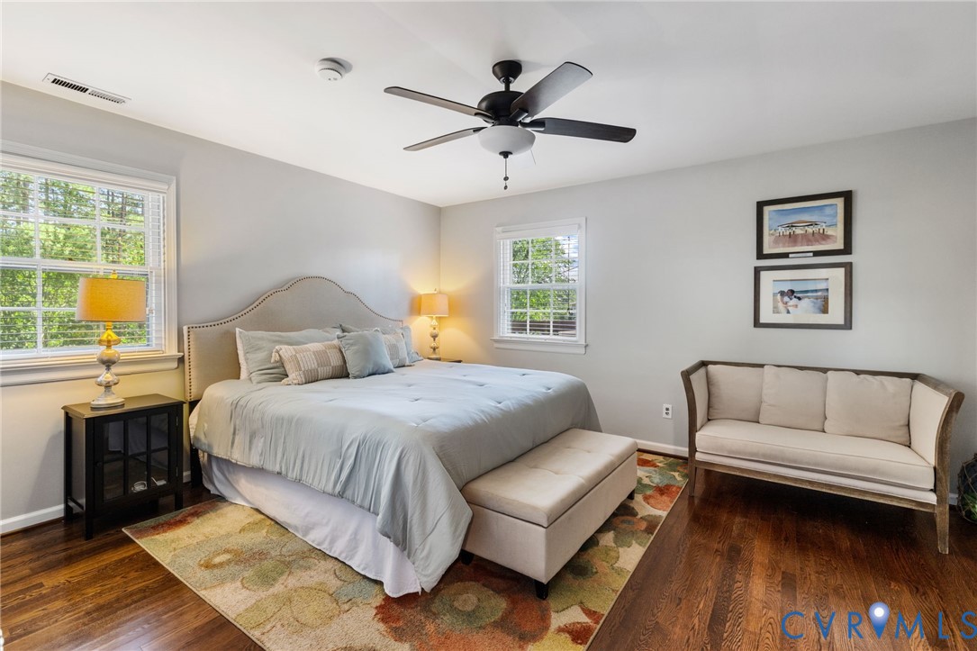 Hardwood flooring, multiple windows, ceiling fan, and neutral wall tones.