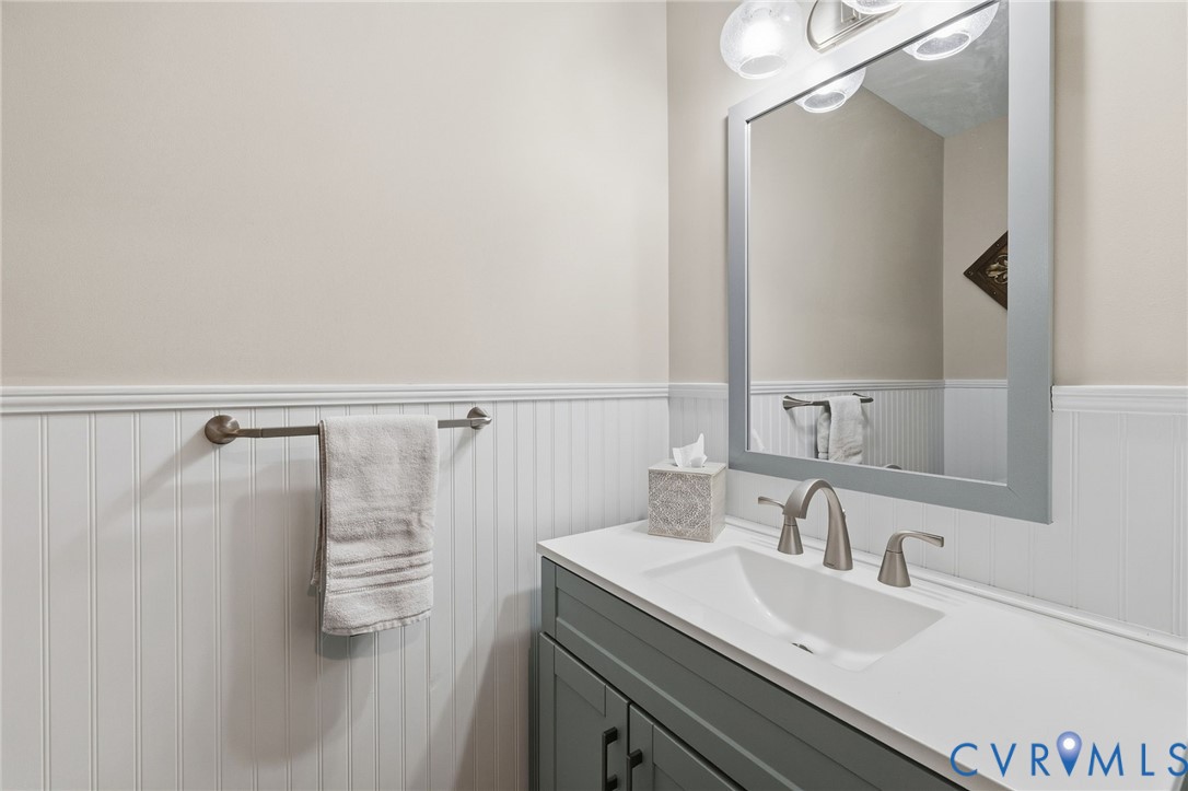 Vanity with integrated sink, brushed nickel faucet, framed mirror, and beadboard wainscoting
