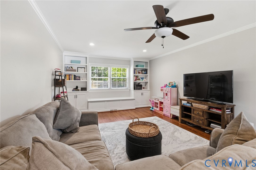 Recessed lighting, crown molding, and built-in shelving with lower cabinetry