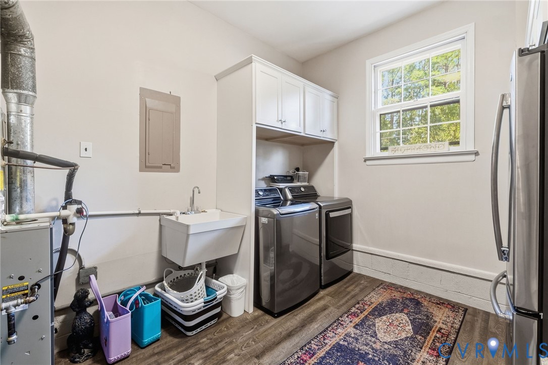 Utility room featuring a wall-mounted sink, LVP flooring, and upper cabinetry