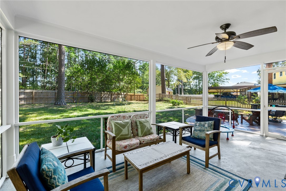 Screened porch featuring a ceiling fan with integrated lighting, concrete flooring, and an expansive view of the fenced backyard