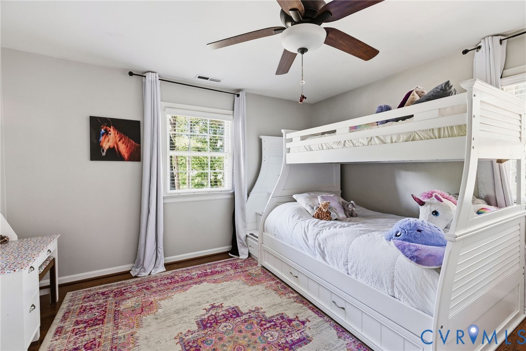 Hardwood flooring, white trim, window with blinds, ceiling fan with light fixture, light gray wall paint