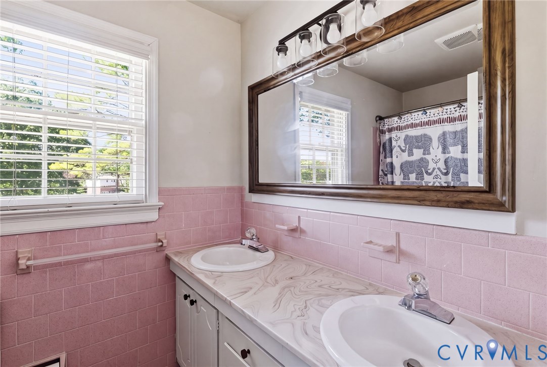 Dual vanity, a patterned countertop, and a wood-framed mirror