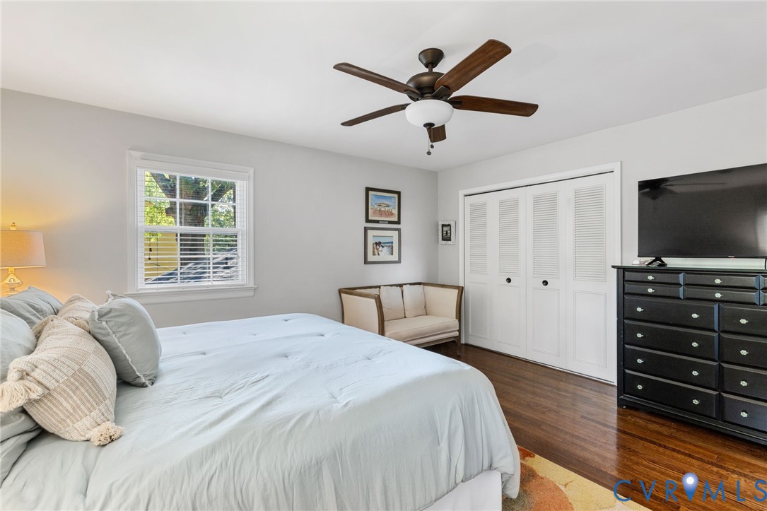 Hardwood flooring, white louvered closet doors, window with blinds, ceiling fan with integrated lighting