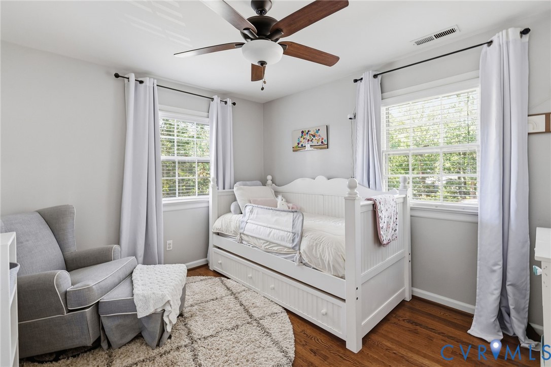 Hardwood flooring, painted walls, two windows, ceiling fan with light fixture, and a built-in daybed with pull-out storage