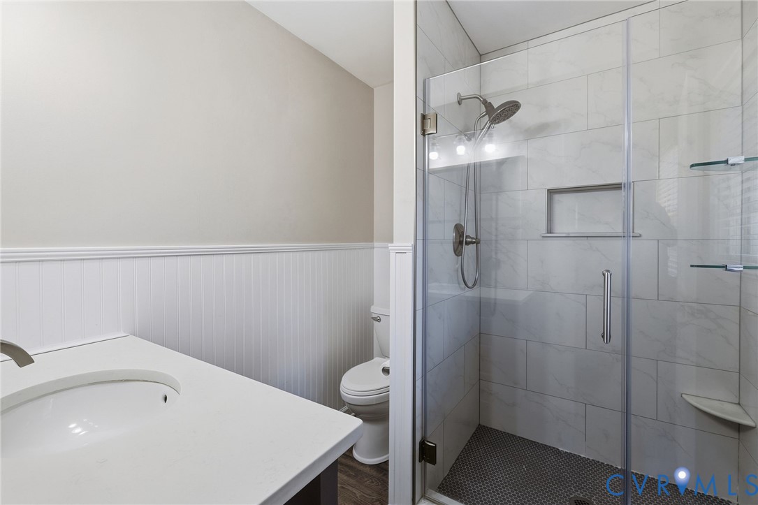 Walk-in shower with clear glass enclosure, tiled walls, and built-in shelving