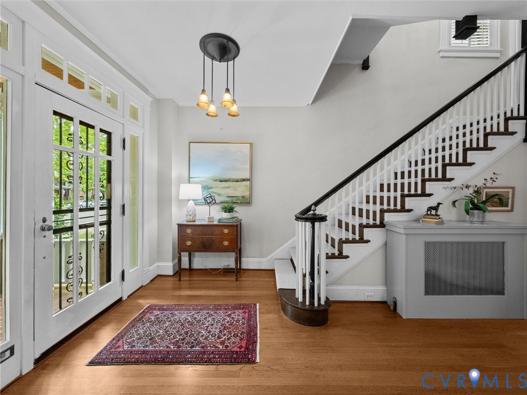 Wood-finish flooring throughout the entry, staircase with white risers and dark wood treads, white balusters, and dark wood handrail